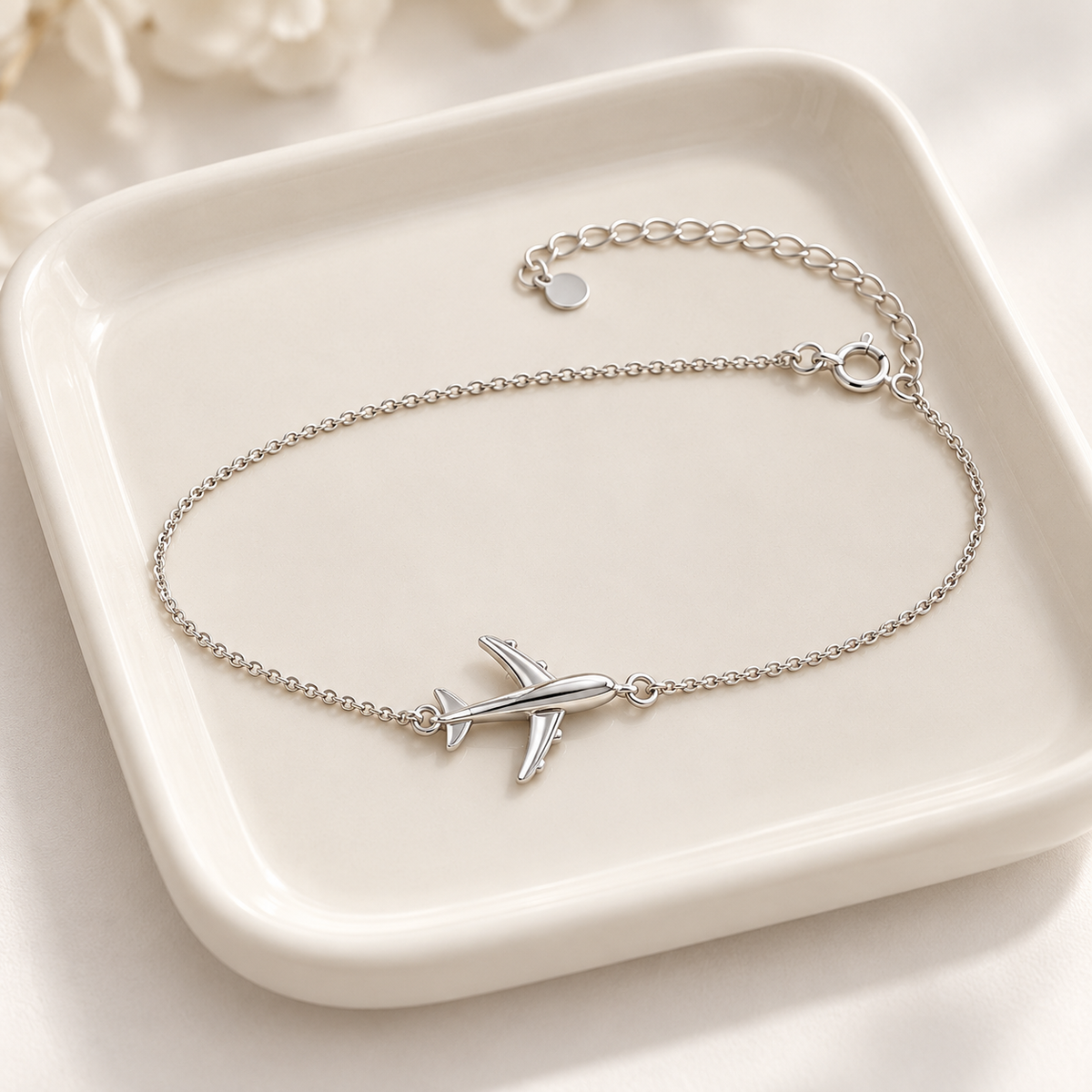 Silver airplane bracelet on ivory tray