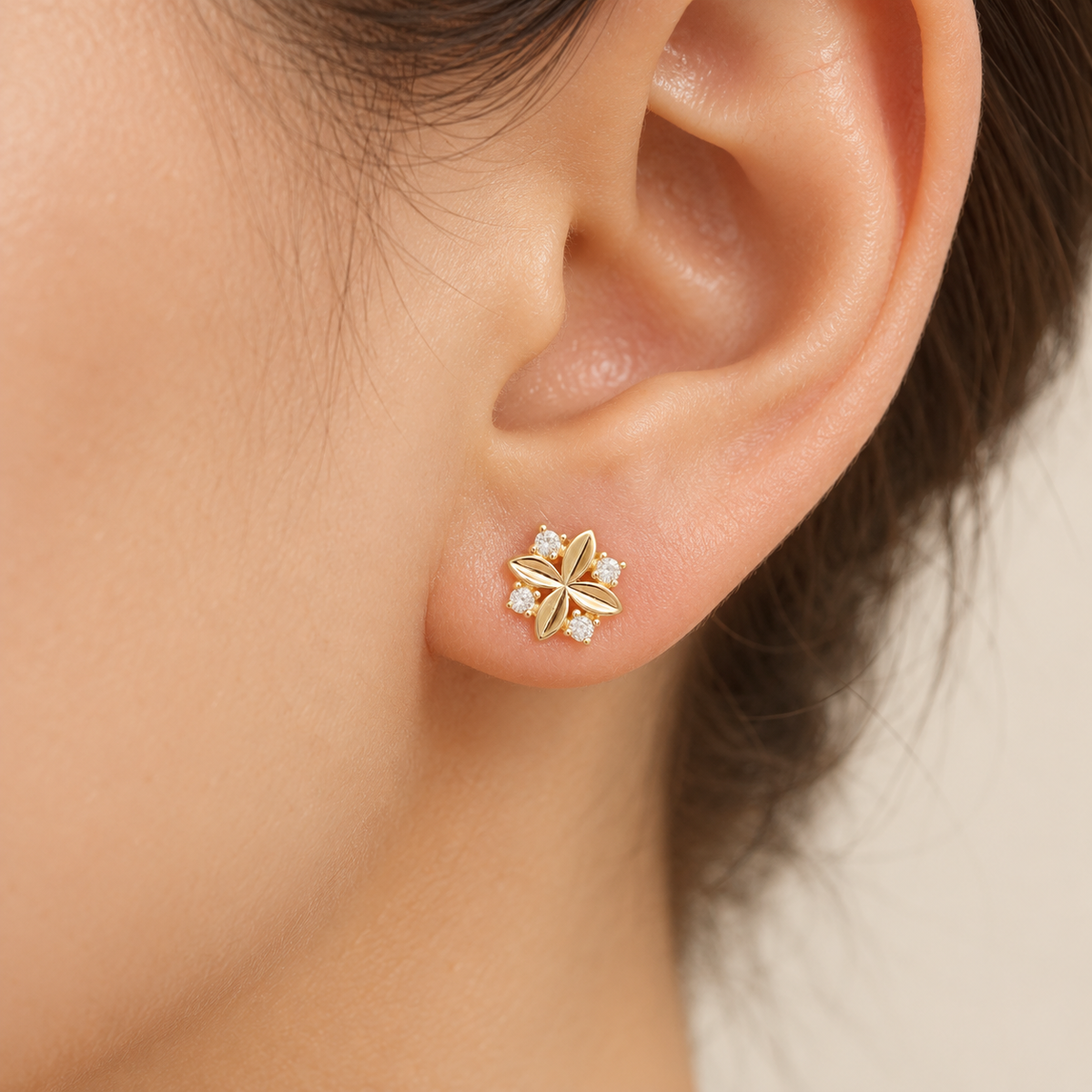 Gold four-petal stud on model ear