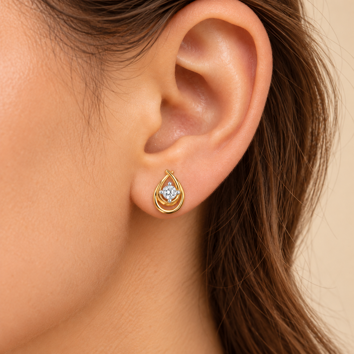 Small gold teardrop stud worn on earlobe