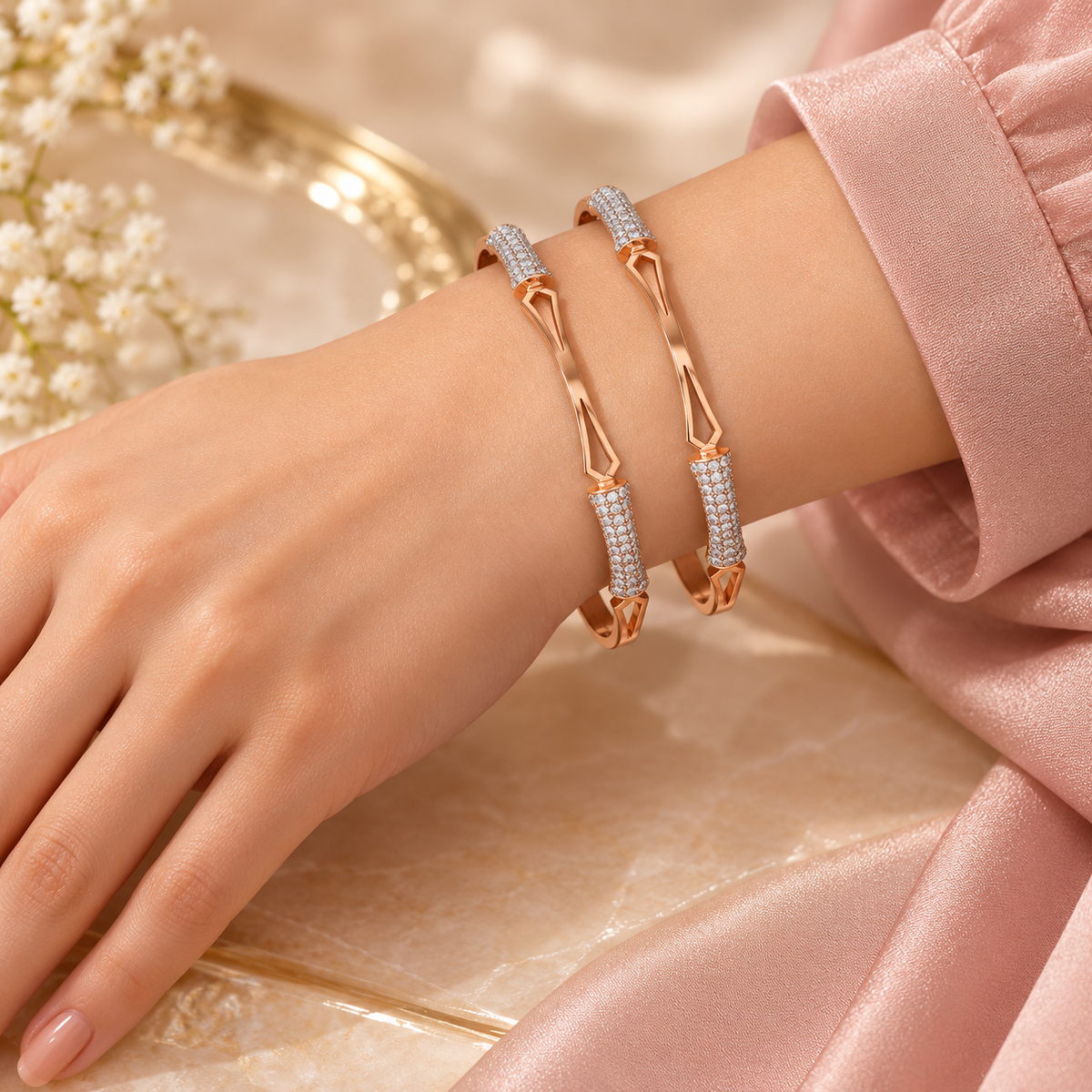 Two rose gold geometric sparkle bangles on model hand