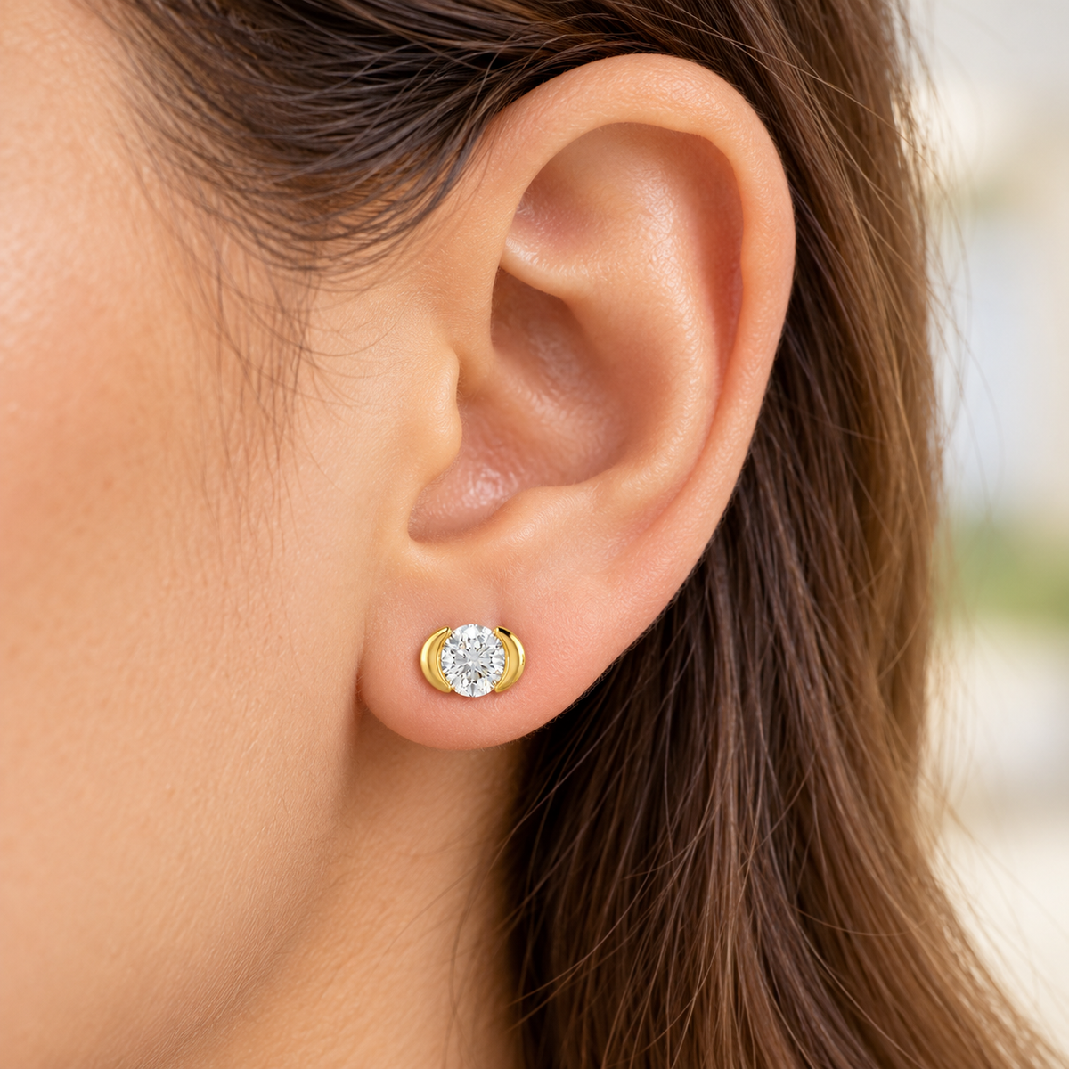 Gold stud worn on model earlobe