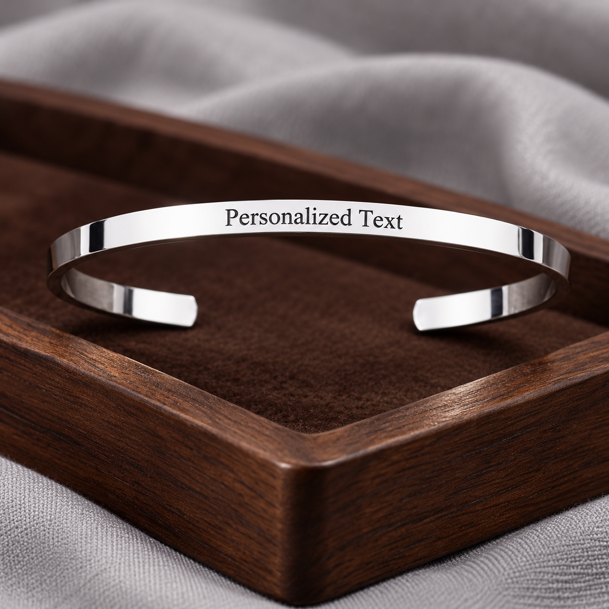 Engraved adjustable silver cuff on walnut tray