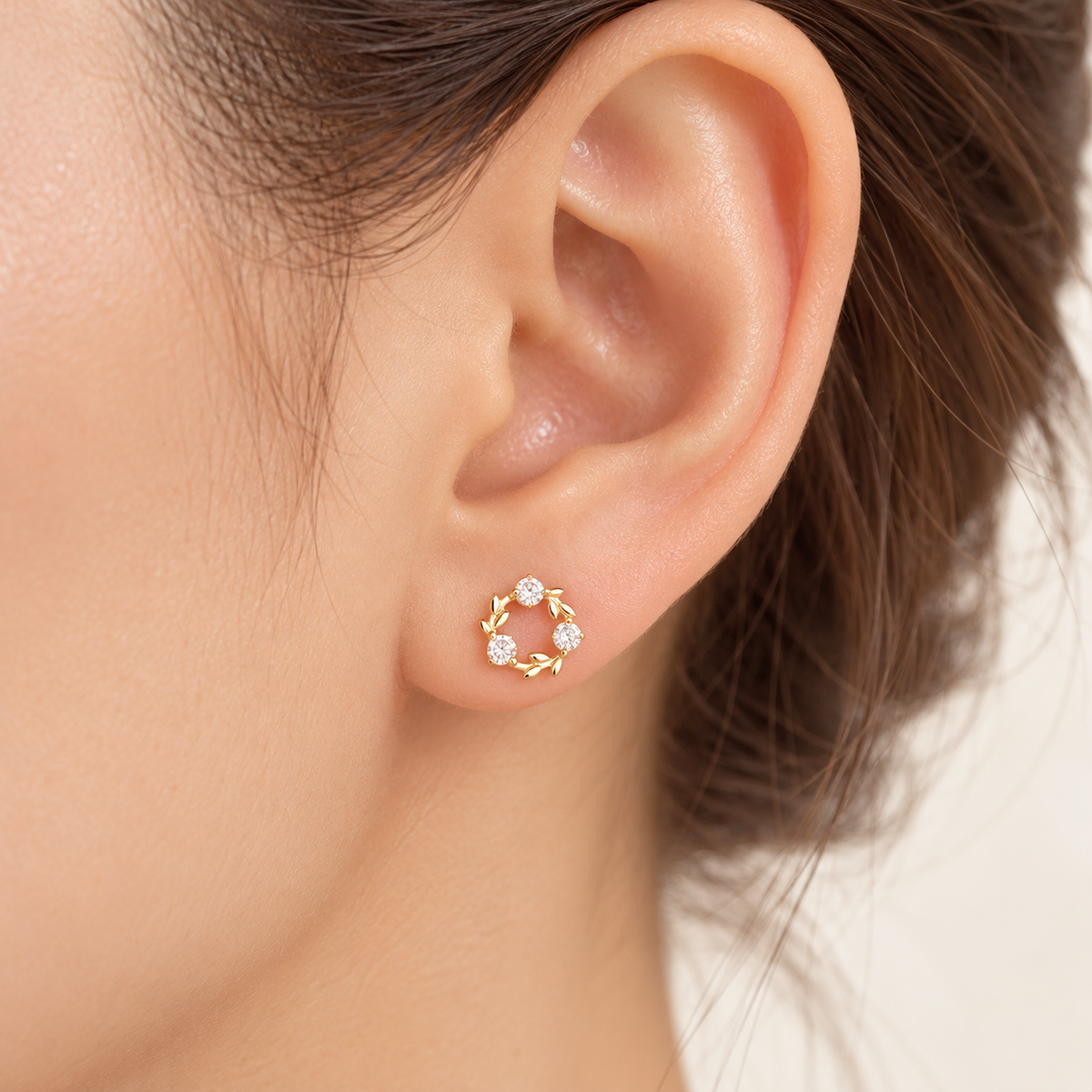 Gold three-stone wreath stud on model ear